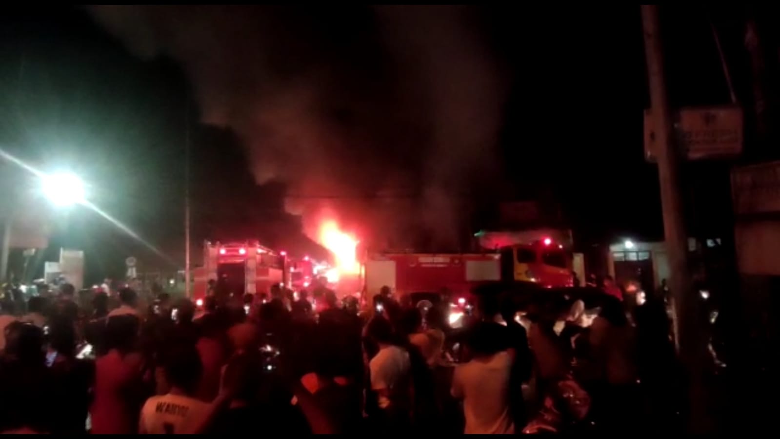 Pengendara berhenti untuk merekam toko onderdil motor yang terbakar, Jumat (11/2/2022)